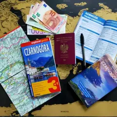 Paszport, pieniądze i przewodniki po Czarnogórze leżą na mapie świata. Czy do Czarnogóry potrzebny jest paszport? Tak, ten polski paszport jest gotowy do podróży!