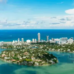 Piękna miami pogoda, błękitne niebo i turkusowa woda otaczają wyspy z luksusowymi willami i drapaczami chmur.